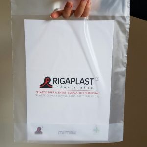 Sujetando una bolsa de plástico con asa tipo troquel y logo rigaplast. Se pueden personalizar